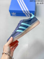 Side profile showing the low-top silhouette, turquoise three stripes, navy upper, and translucent gum outsole.