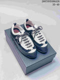 Pair of black-and-white low-top Chanel trainers displayed on a box, showing the rounded toe and contrasting laces.