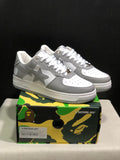 Pair of white and grey BAPE Sta low-top sneakers displayed on a camouflage BAPE shoebox; the box label shows EU 41 and CM 26.