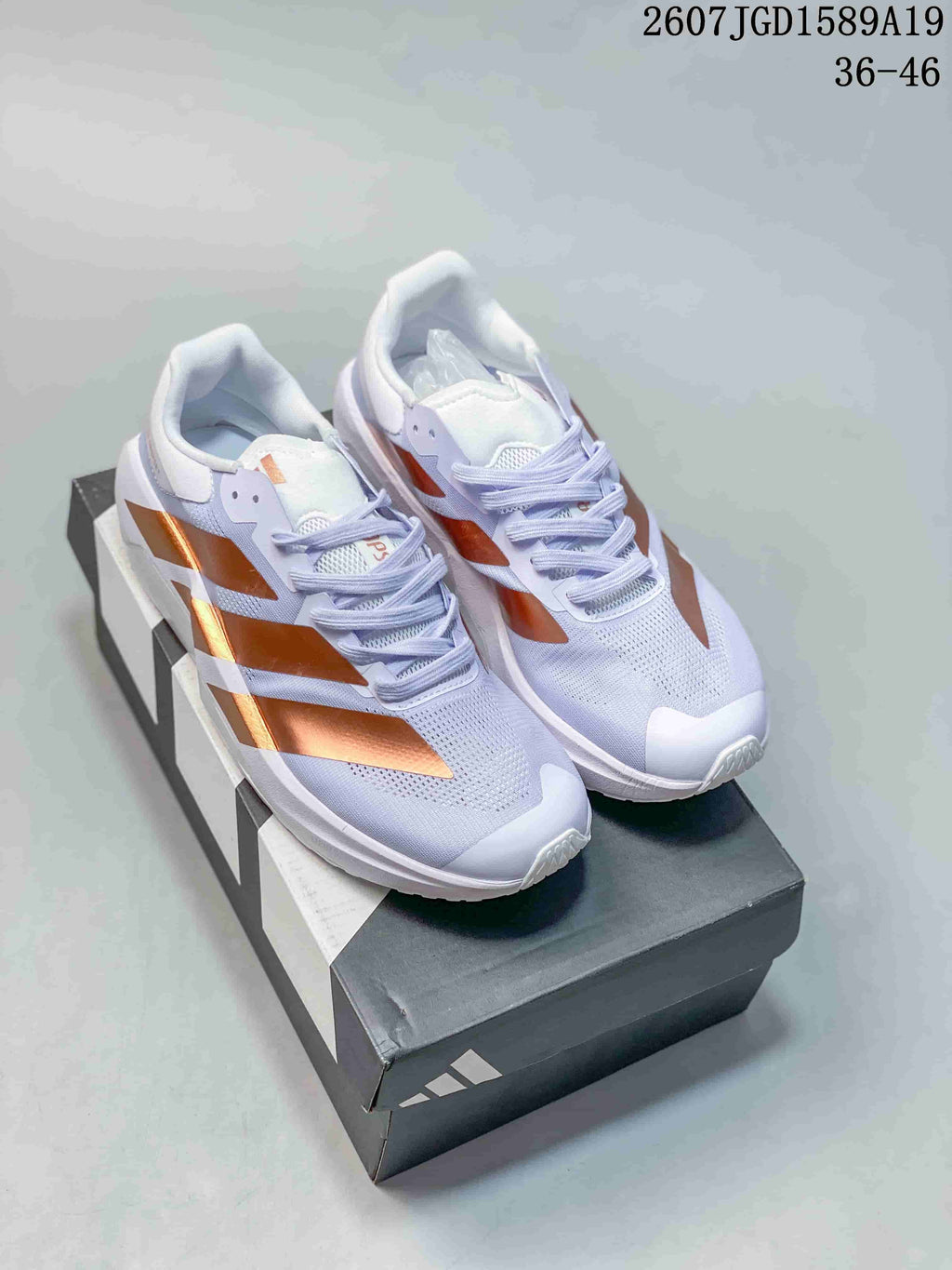 Pair of white adidas training sneakers with metallic copper side accents shown on a shoebox; image text indicates 36–46.