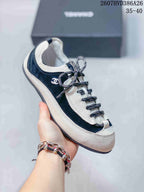 Side view of a black and white low-top sneaker showing the decorative side logo, rounded toe, and patterned laces.