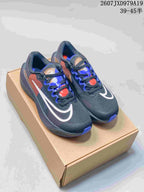 Pair of dark charcoal Nike running shoes with blue, white, red and tan details displayed on a cardboard box.