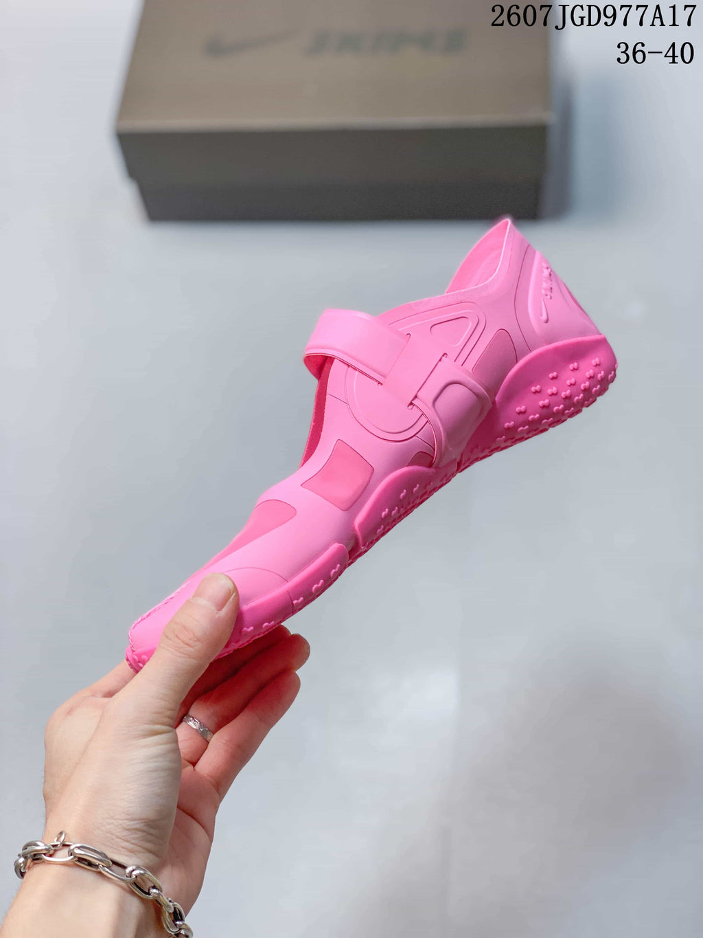 Side view of the pink split-toe sneaker showing the adjustable strap, layered upper panels and textured sole.