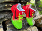 Angled view of the red and green Kobe 6 shoes with black Swooshes and white tongue logos