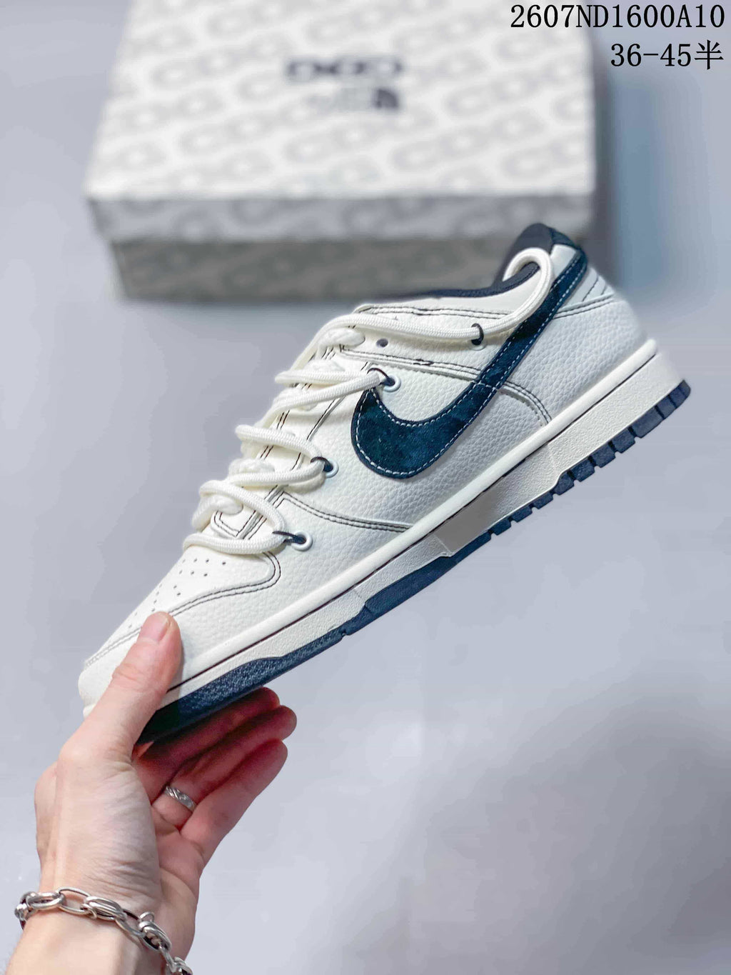 Side view of the white low-top sneaker with a navy Swoosh, stitched panels and dark outsole.