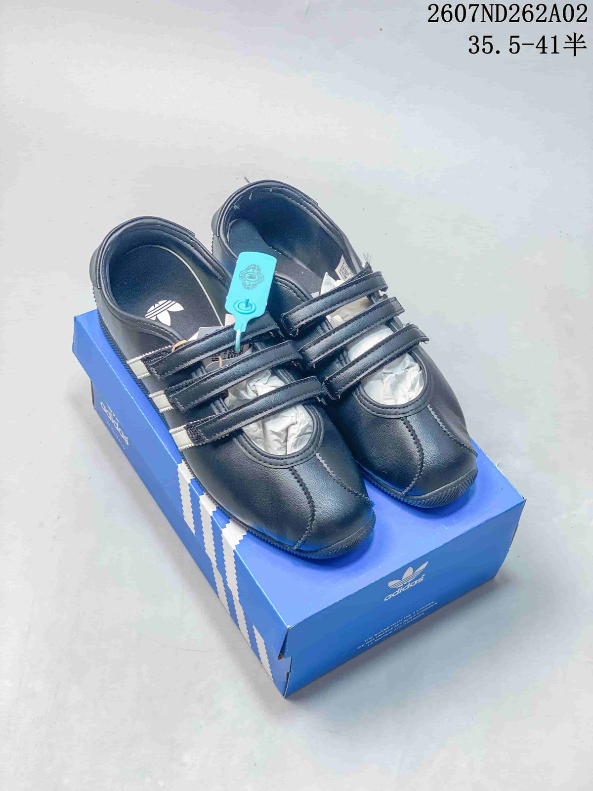 Black adidas Originals ANFU MJ sneakers with three straps, shown on a blue shoebox