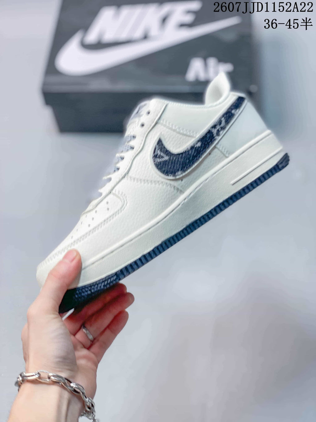 Side view of the white low-top sneaker showing the dark patterned side panel, white midsole, and dark outsole.