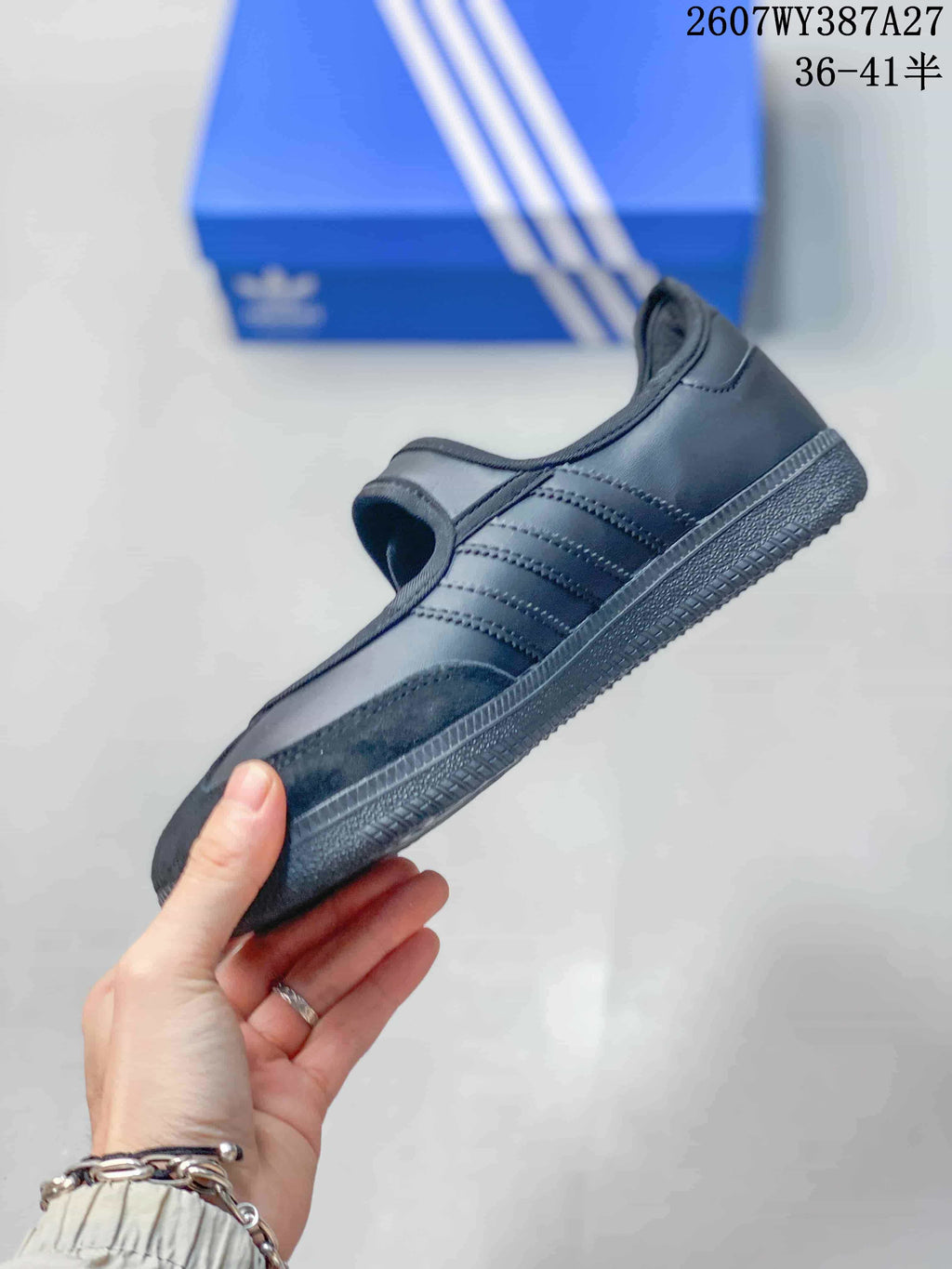 Side view of the black sneaker showing the tonal three-stripe details, low profile and rubber outsole.