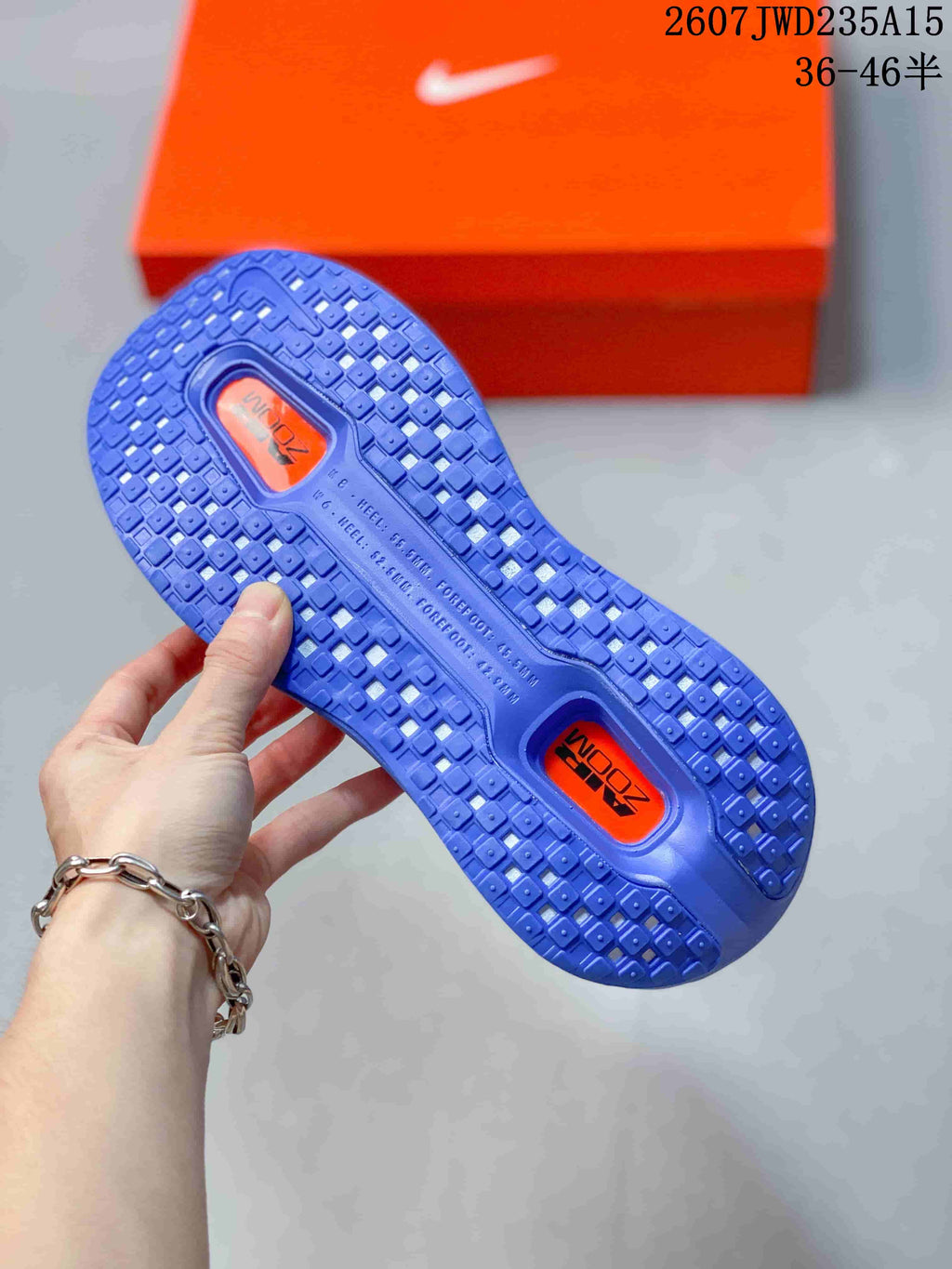 Underside view of a blue Nike running shoe outsole with textured tread and orange inserts.