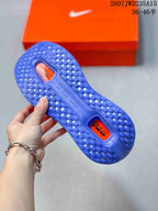 Underside view of a blue Nike running shoe outsole with textured tread and orange inserts.