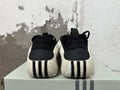 Rear view of black sneakers with white heel panels and ribbed details