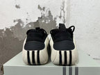 Rear view of black sneakers with white heel panels and ribbed details