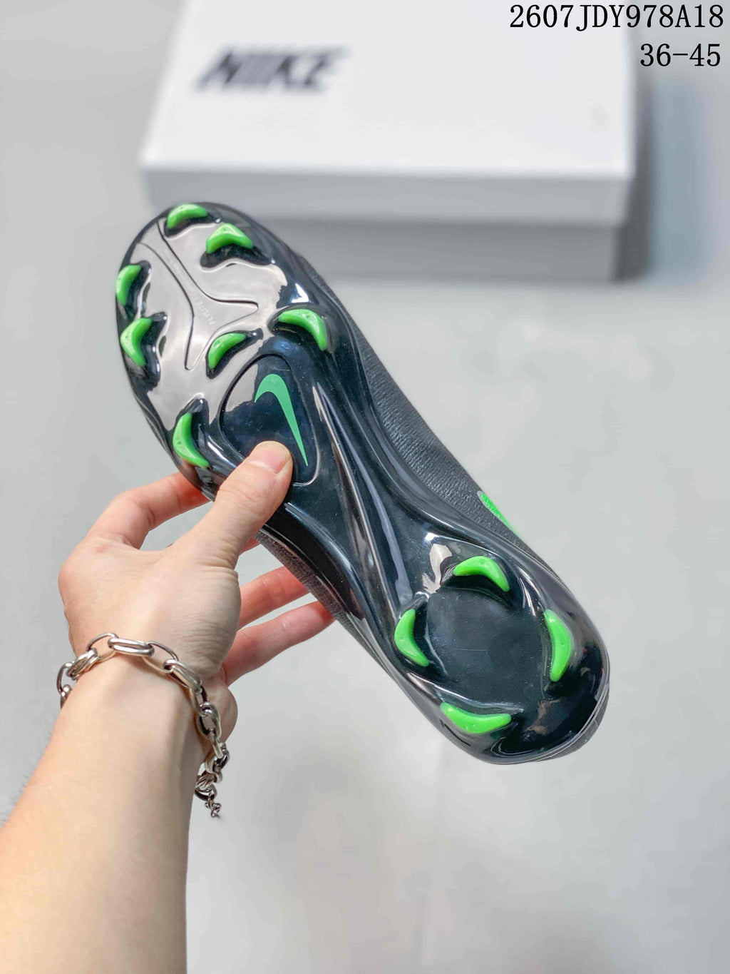 Close-up of the black outsole showing multiple green-tipped soccer cleats and stud placement.