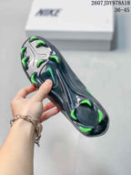 Close-up of the black outsole showing multiple green-tipped soccer cleats and stud placement.