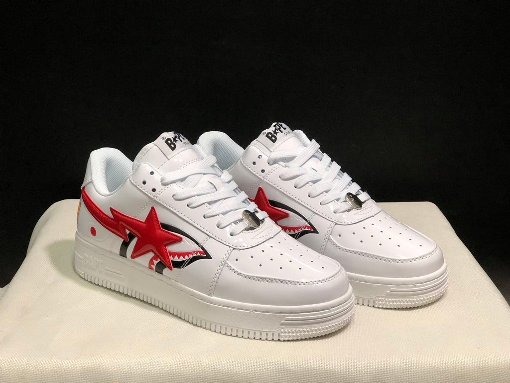 Front three-quarter view of the white and red low-top sneakers with perforated toe panels and padded collars.