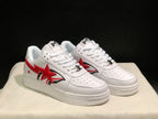 Front three-quarter view of the white and red low-top sneakers with perforated toe panels and padded collars.
