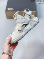 Side profile of the sandal showing layered straps, open side panels, mesh sections, and a textured outsole.