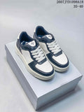 Pair of white and navy SMFK low-top sneakers displayed on a shoebox, with the style code and size range visible above.