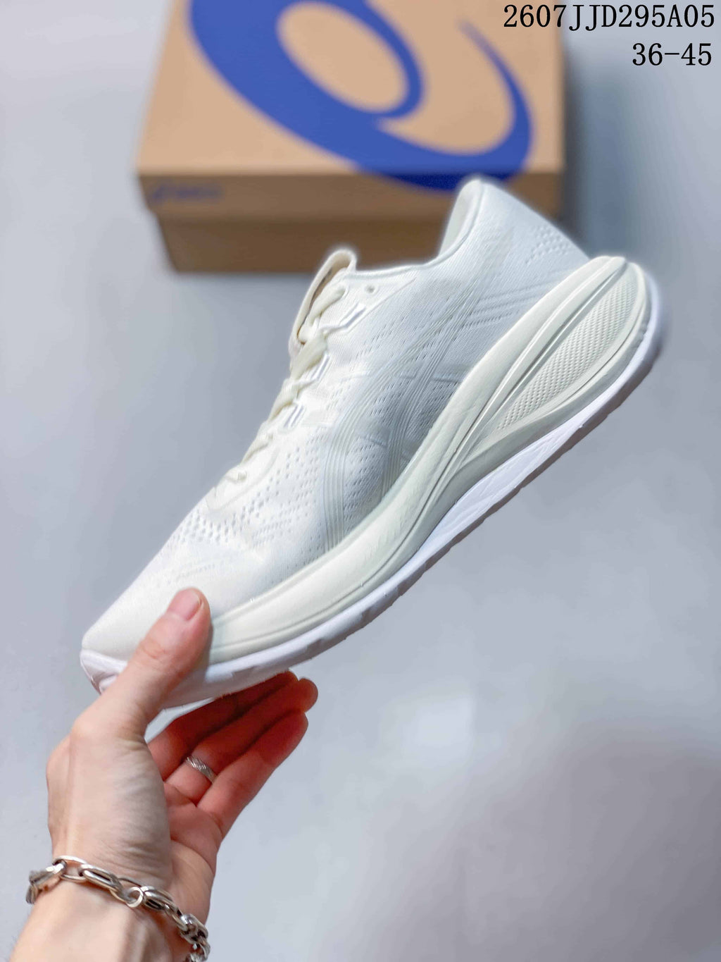Side profile of the white ASICS running shoe showing the mesh-style upper and layered midsole; image text shows code 2607J JD295A05 and size range 36–45.