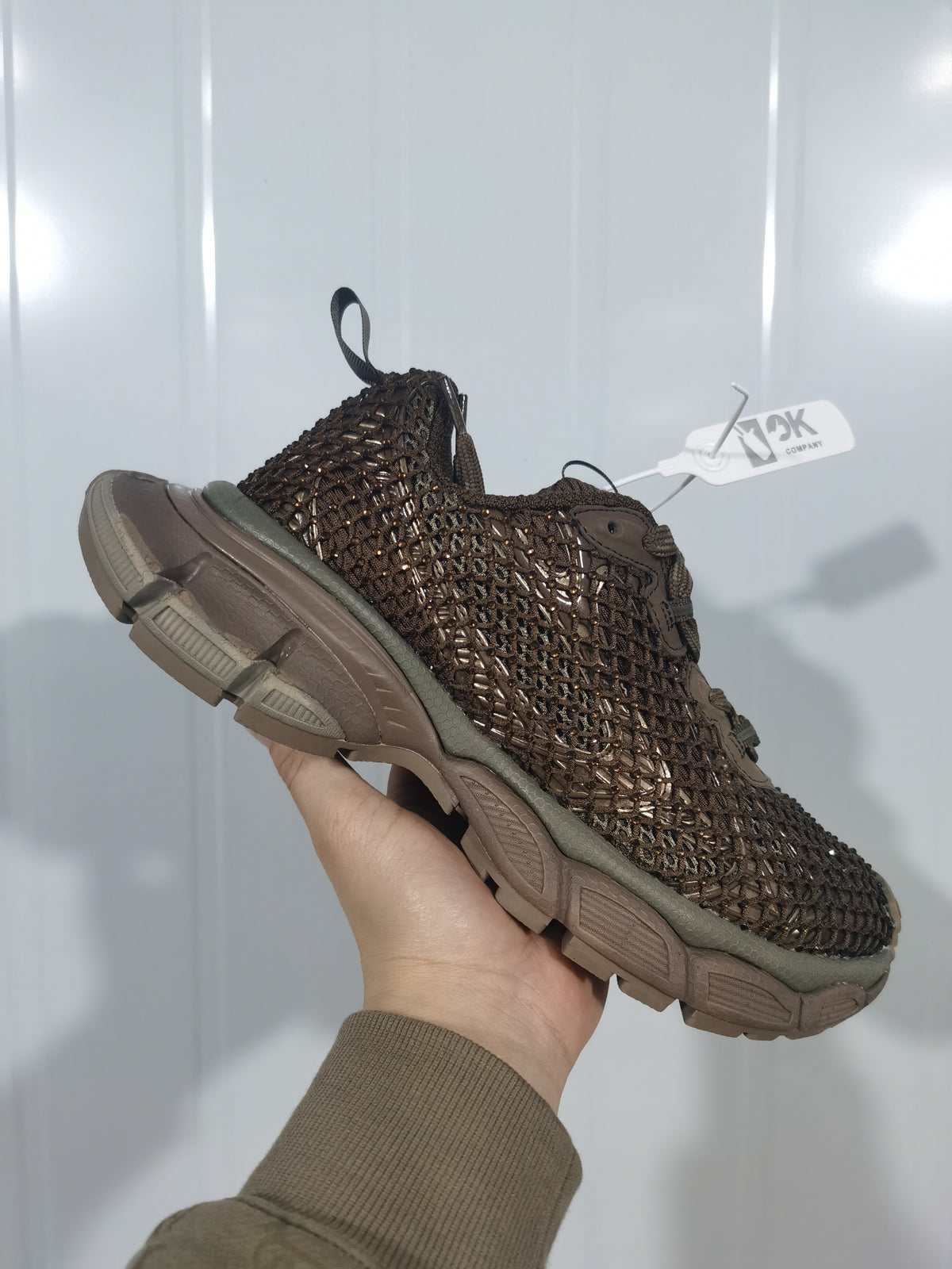 Side and heel view of the brown textured sneaker showing the layered upper, rear pull loop, and chunky tonal outsole.