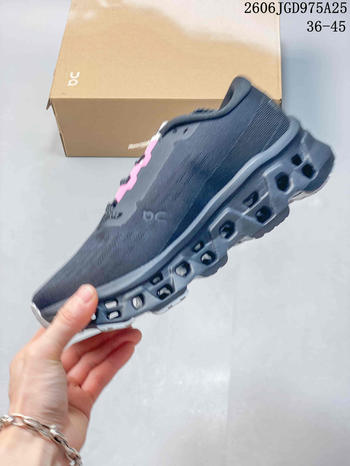 Side view of a charcoal running shoe with pink lace-panel accents and a cutout-style sole.