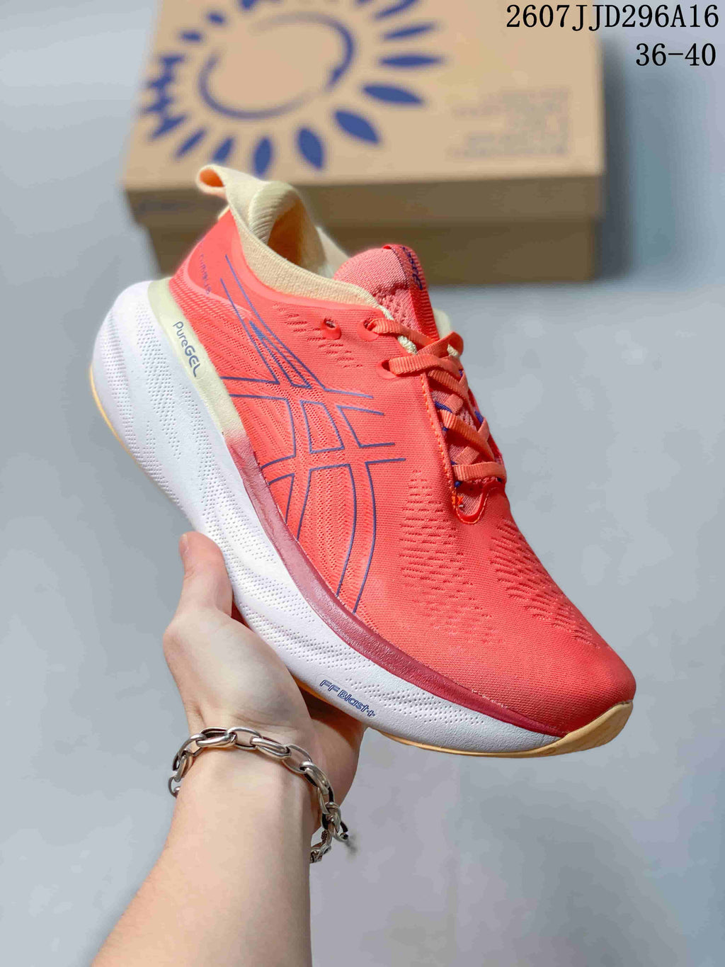 Angled side view of the coral pink ASICS GEL-Nimbus 25 shoe showing the blue logo, white midsole and visible PureGEL and FF BLAST+ markings.