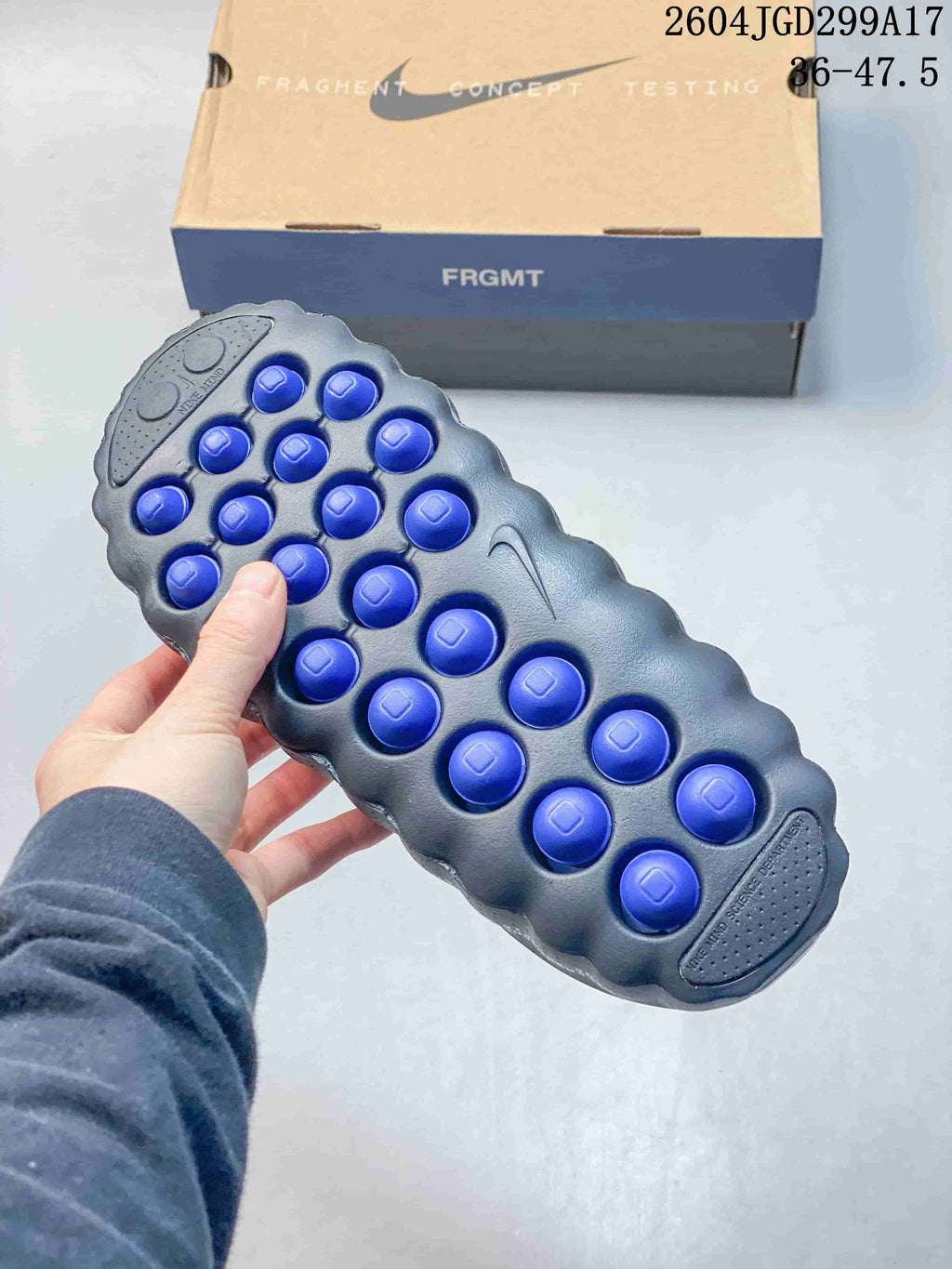 Underside view of a slide showing multiple blue circular outsole elements and the printed size range 36–47.5.