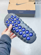 Underside view of a slide showing multiple blue circular outsole elements and the printed size range 36–47.5.