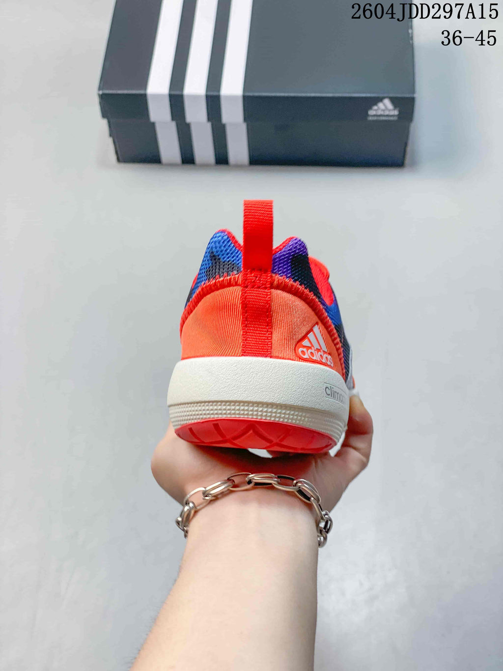 Rear view showing the orange heel, red pull tab, white midsole and coral outsole.