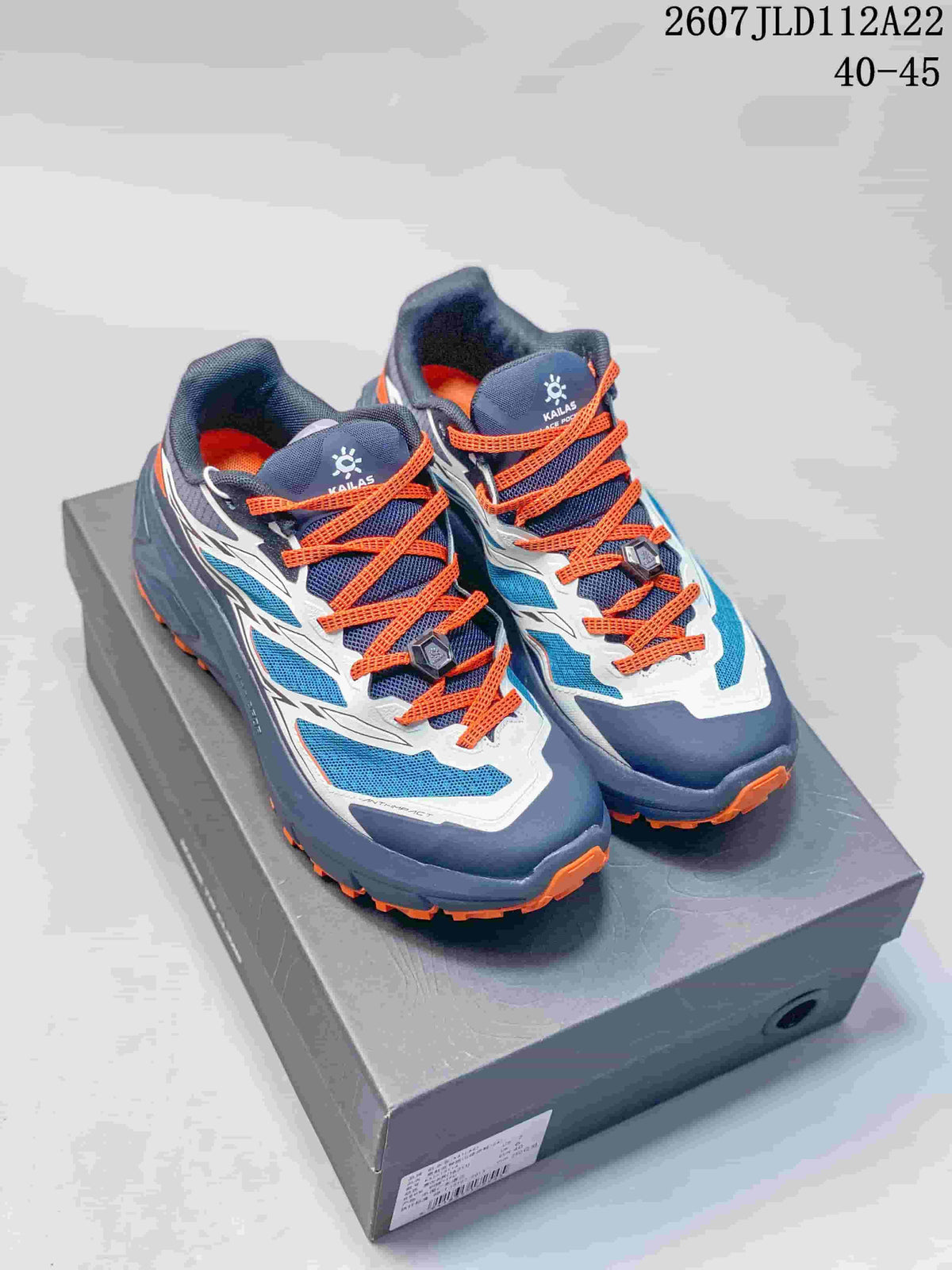 Pair of navy, blue, white, and orange Kailas C4 sneakers displayed on a shoebox, with the size range and style code visible above.