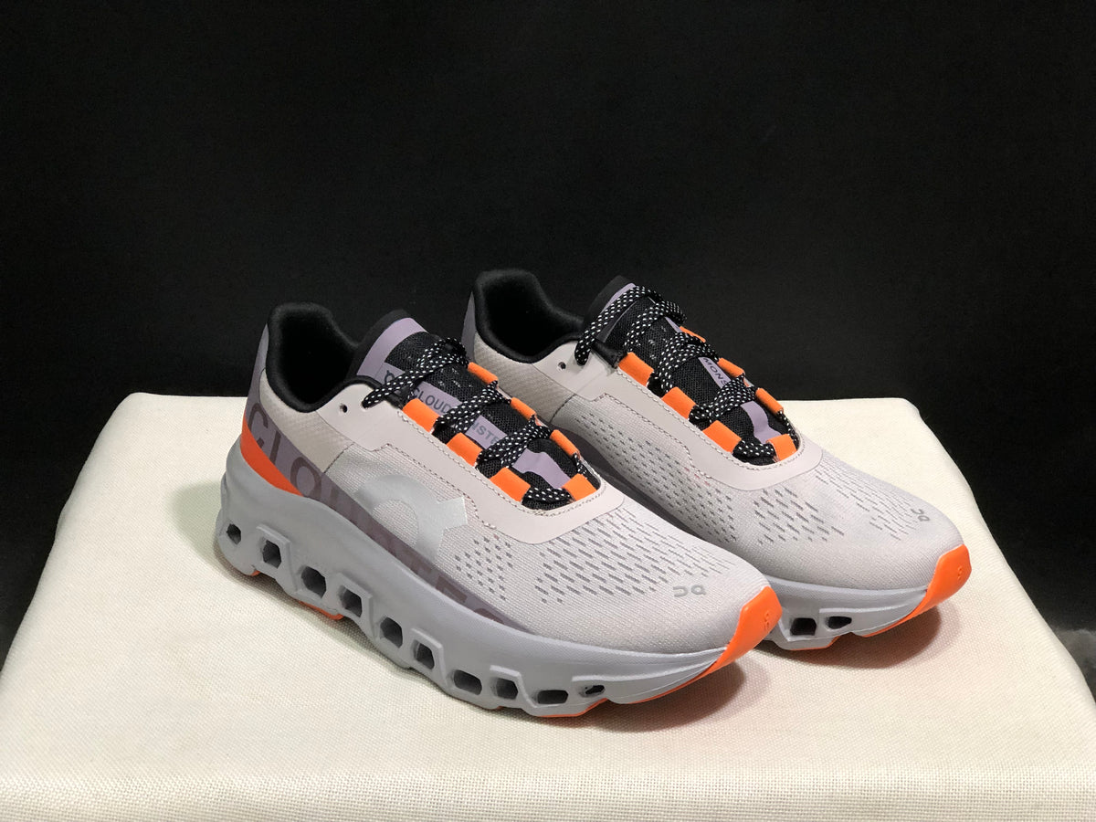 Angled view of the gray On Cloud X pair with orange details and open sections in the sole.