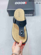 Top view of one black thong sandal with a tan textured footbed, buckle strap, and central toe post.