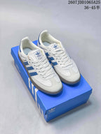 Pair of white and blue Adidas Samba sneakers displayed on a blue shoebox.