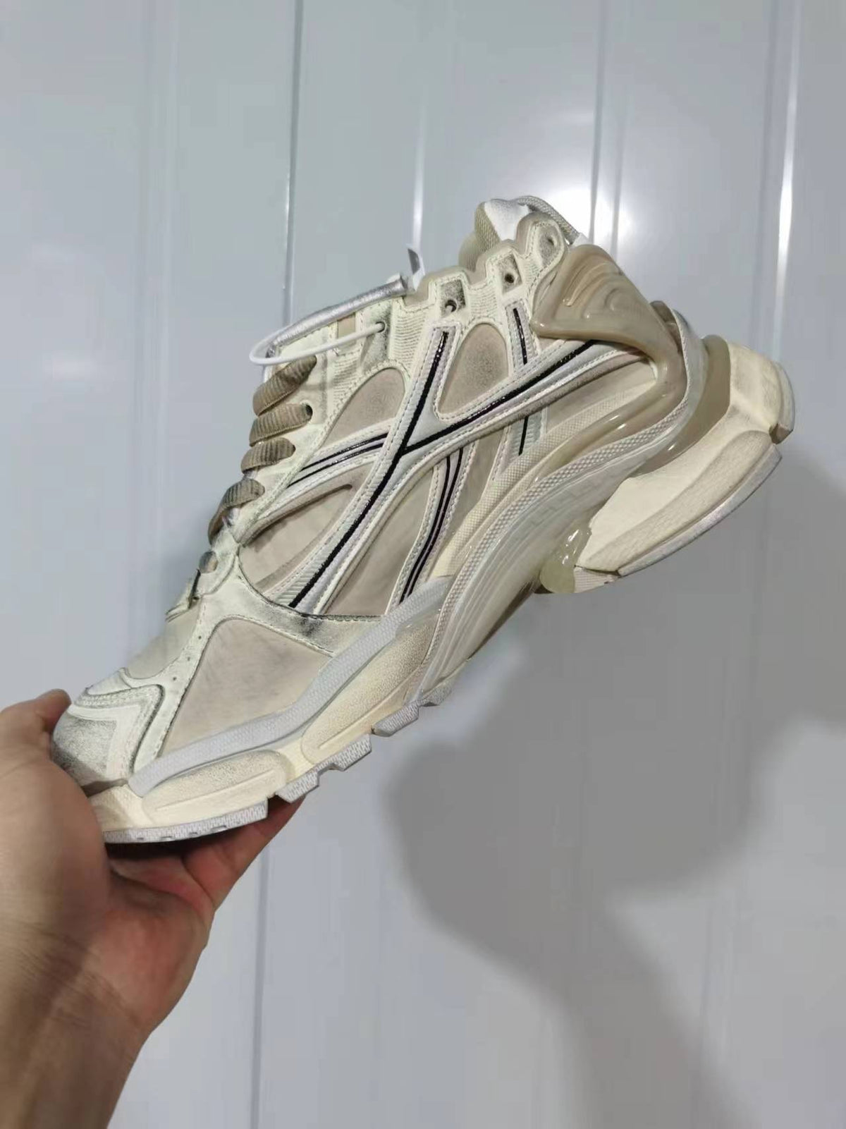 Angled rear-side view showing the layered upper, padded heel structure, contrasting line details, and textured outsole of the Reebok 1205 sneaker.