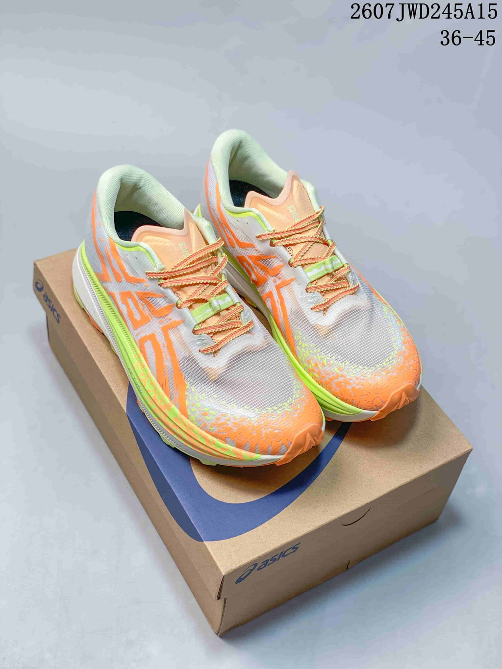 Pair of ASICS GEL-MAGIC SPEED 4 CP sneakers in white, orange and lime displayed on an ASICS shoebox; image text shows code 2607TWD245A15 and sizes 36–45.