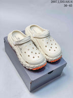 Pair of off-white Balenciaga-branded clog sandals displayed on a shoe box, with orange tread sections and the style code 2607JJD514A14 visible above.