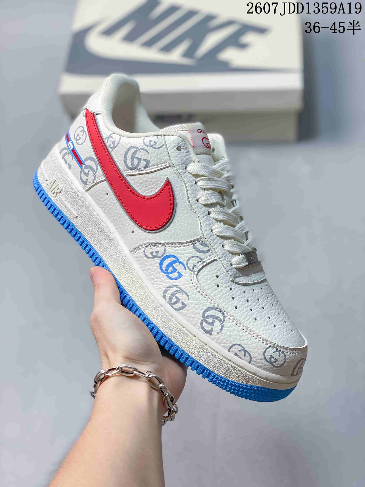 Close-up of a white low-top sneaker with gray patterned graphics, red Swoosh, white laces, and a bright blue outsole; image text shows style code 2607JDD1359A19 and size range 36-45.