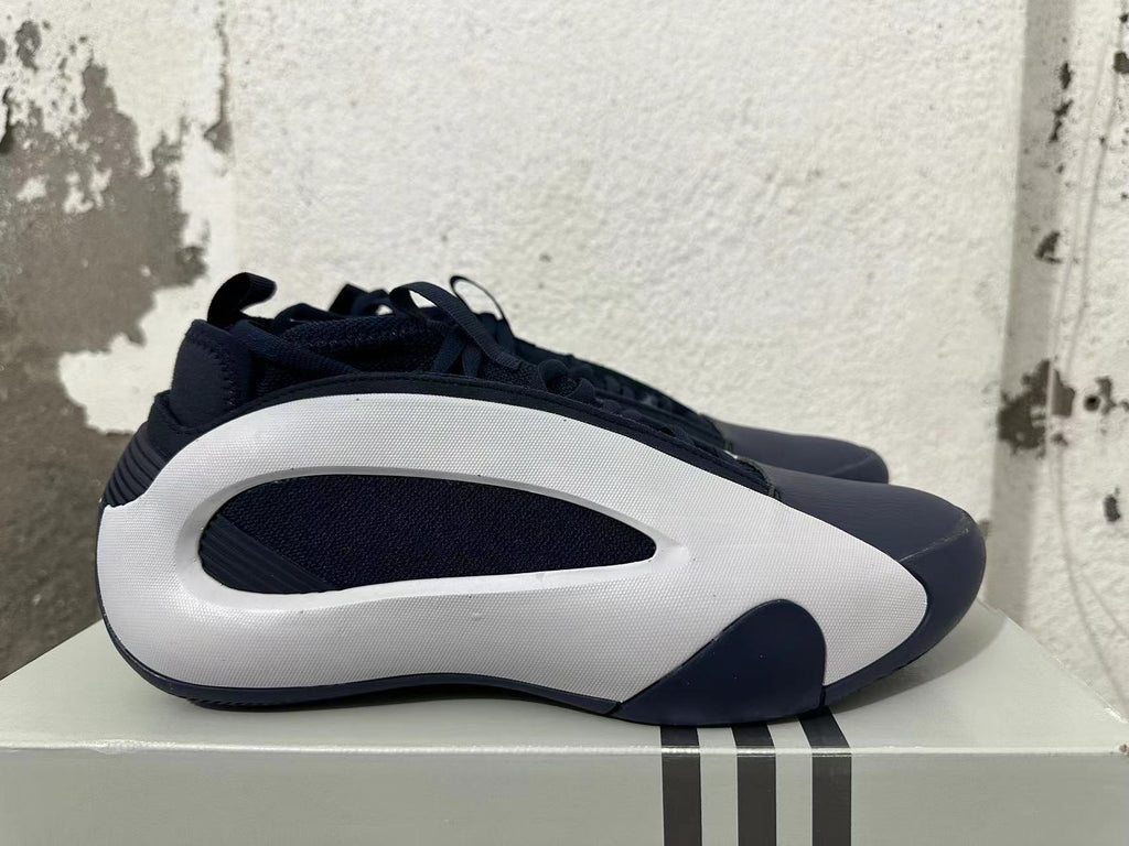 Side view of navy and white Adidas basketball shoes with sculpted white side panels.
