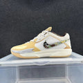 Low-top Nike basketball shoe in white and pale yellow, with a patterned side Swoosh and visible Zoom marking.