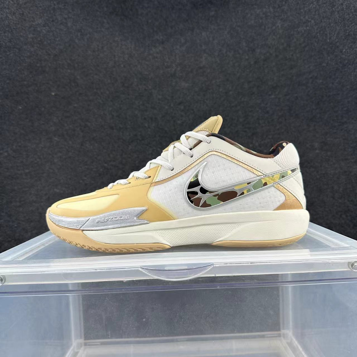 Low-top Nike basketball shoe in white and pale yellow, with a patterned side Swoosh and visible Zoom marking.