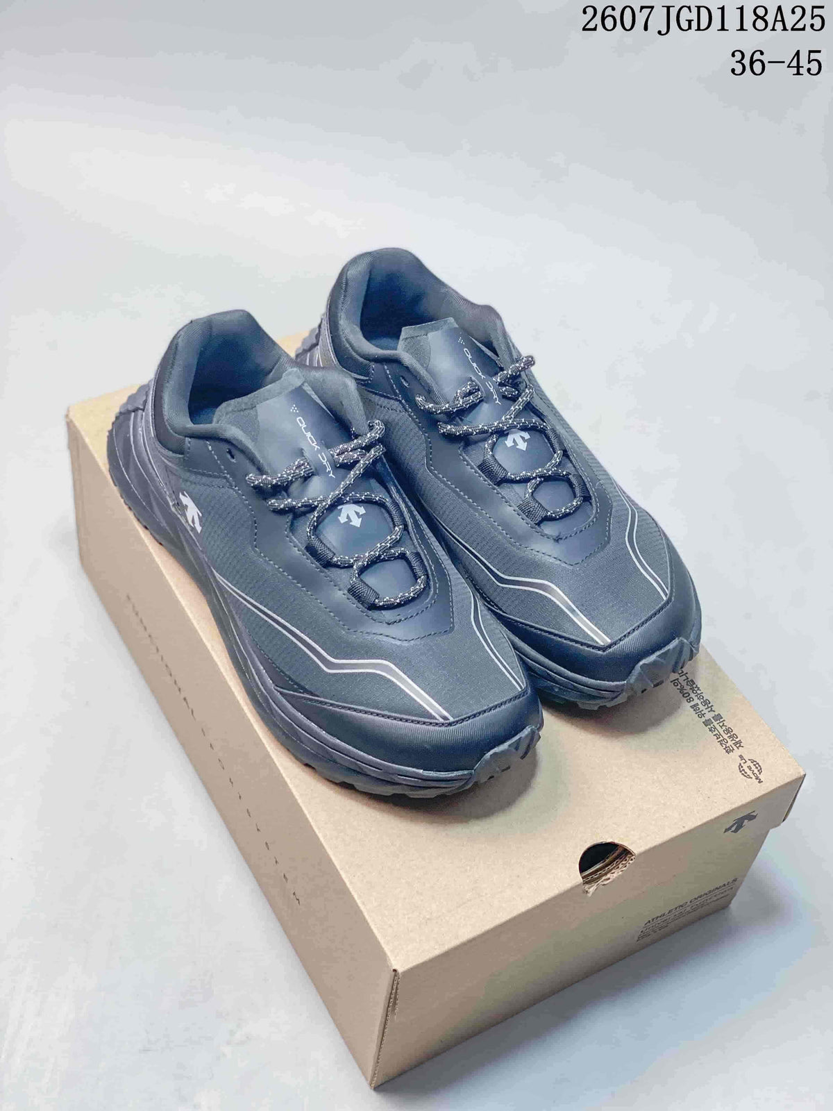 Pair of dark gray DESCENTE low-top hiking shoes displayed on a shoe box, with the outsole and reflective-looking upper accents visible.