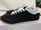 Side view of black low-top sneakers with white laces, white collar details, and a gum-colored outsole.