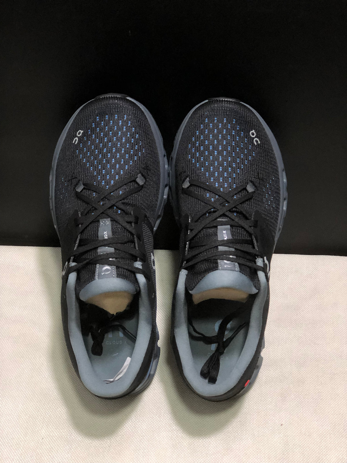 Top view showing the black textured uppers, blue detailing, laces, and gray collars.