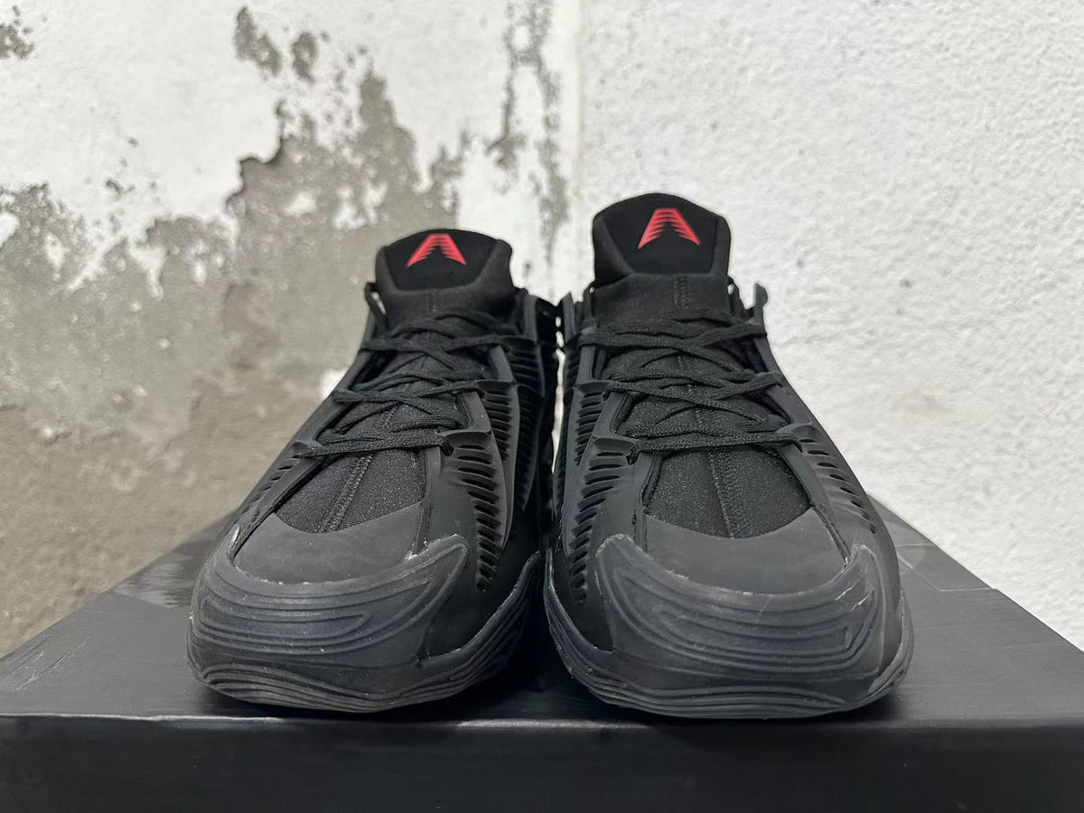 Front view of black Adidas lace-up sneakers with red tongue logos