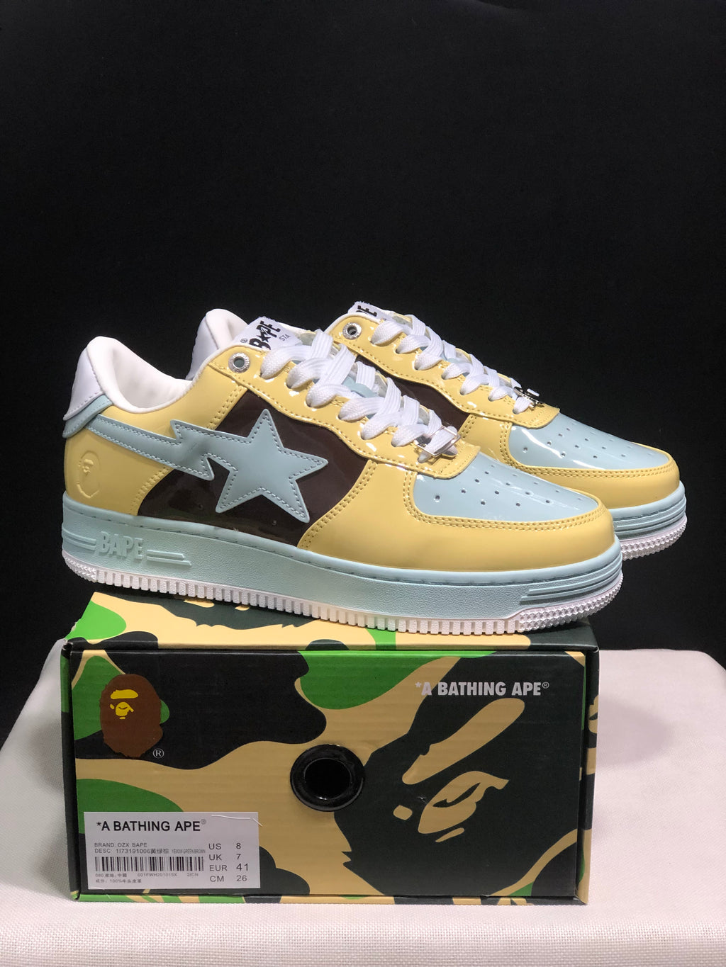 Pair of BAPE STA low-top sneakers in yellow, light blue, brown, and white, displayed above a branded shoebox.
