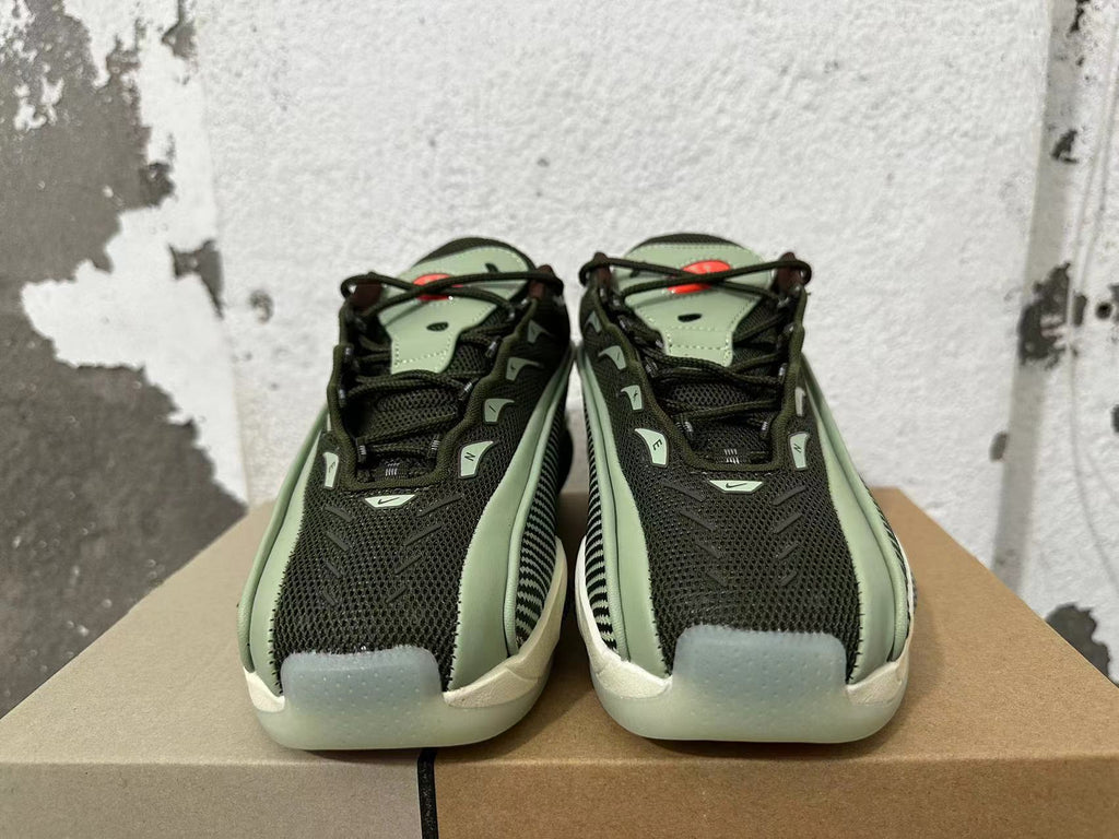 Front view of dark mesh sneakers with green-toned details and cream-colored toe sections.
