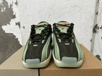 Front view of dark mesh sneakers with green-toned details and cream-colored toe sections.