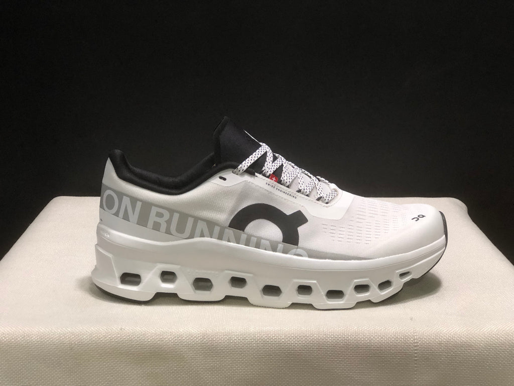 Side profile showing the white sneaker, large side branding, black collar, and layered sole.