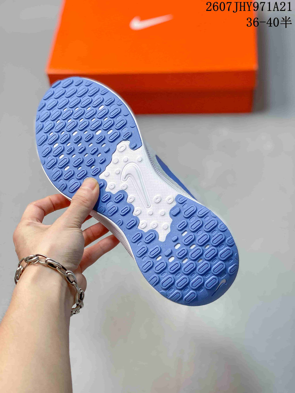 Close view of the blue-and-white patterned outsole on a Nike running shoe, with the orange shoebox in the background.