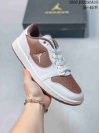 White and brown low-top Jordan sneaker held at an angle, with brown heel and toe panels and a white side-panel logo.